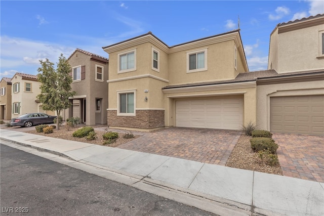 view of front of property with an attached garage, stone siding, decorative driveway, and stucco siding