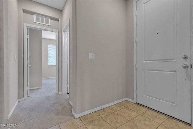 hall with light tile patterned floors, baseboards, visible vents, and light colored carpet