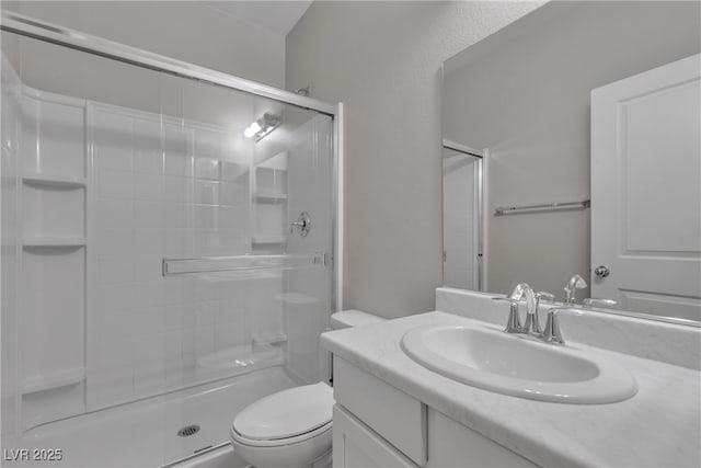 full bathroom with a stall shower, vanity, and toilet