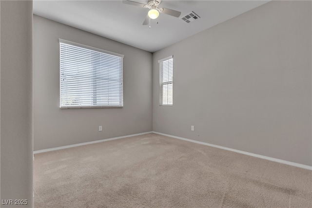 empty room with baseboards, carpet floors, visible vents, and a ceiling fan