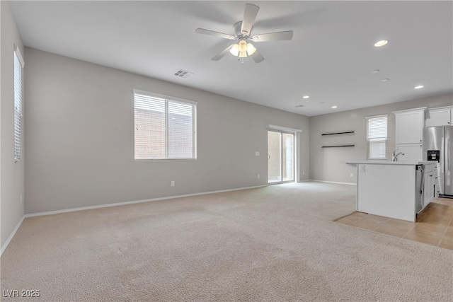 unfurnished living room featuring recessed lighting, light colored carpet, a sink, visible vents, and baseboards