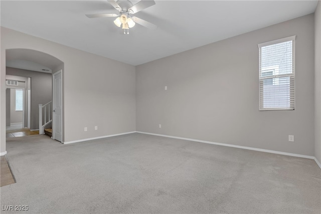 unfurnished room featuring arched walkways, baseboards, carpet flooring, and a healthy amount of sunlight