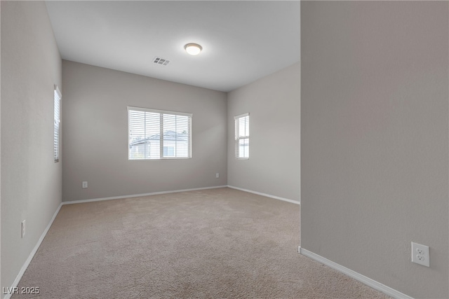 carpeted empty room featuring baseboards and visible vents