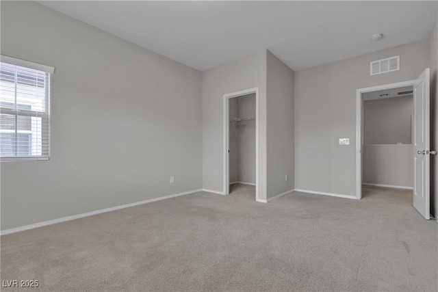 unfurnished bedroom featuring baseboards, visible vents, a walk in closet, and carpet flooring