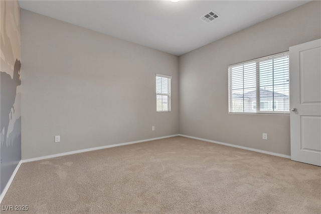 spare room with carpet floors, baseboards, and visible vents