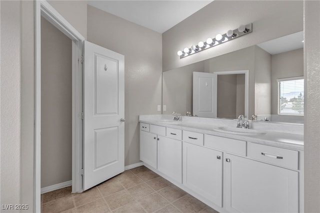 bathroom with double vanity, tile patterned flooring, baseboards, and a sink