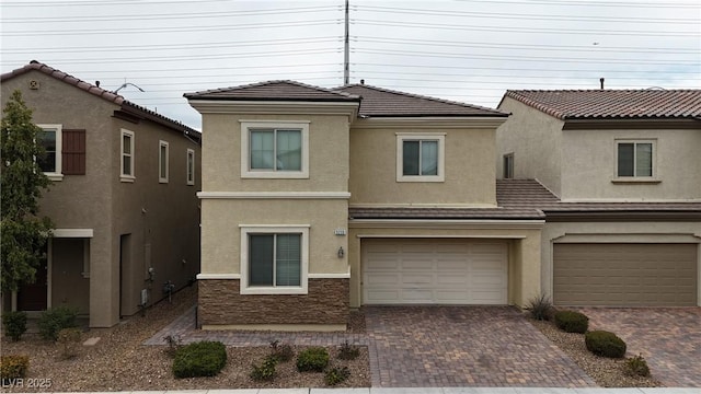 view of front of house with a garage, decorative driveway, and stucco siding