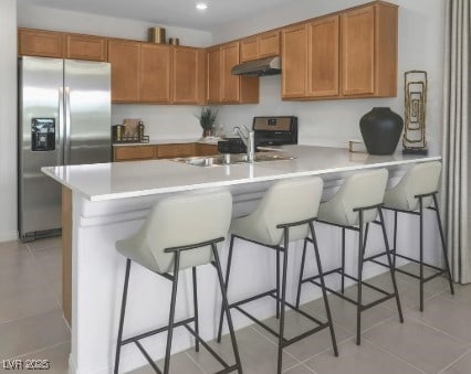 kitchen featuring stainless steel appliances, sink, light tile patterned floors, and a kitchen breakfast bar