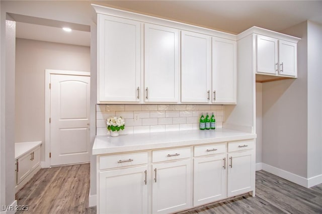 kitchen featuring decorative backsplash, white cabinets, and light wood-type flooring