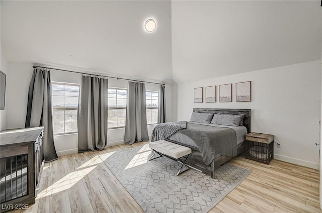 bedroom featuring high vaulted ceiling and light hardwood / wood-style floors