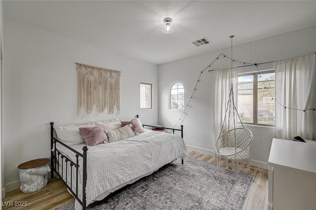 bedroom with multiple windows and light wood-type flooring