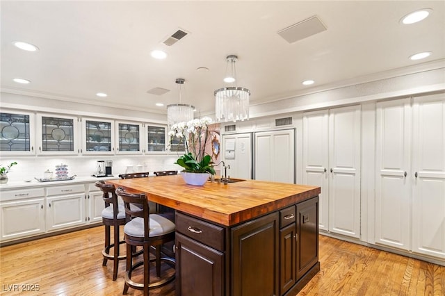 kitchen featuring wooden counters, decorative light fixtures, a center island, dark brown cabinets, and white cabinets