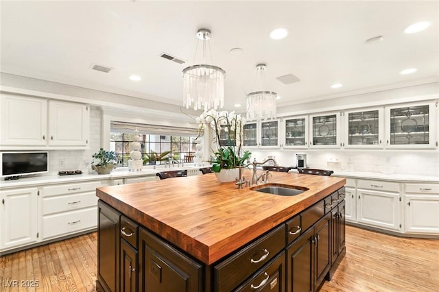 kitchen with white cabinetry, decorative light fixtures, and an island with sink