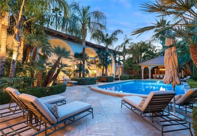 pool at dusk with a patio area