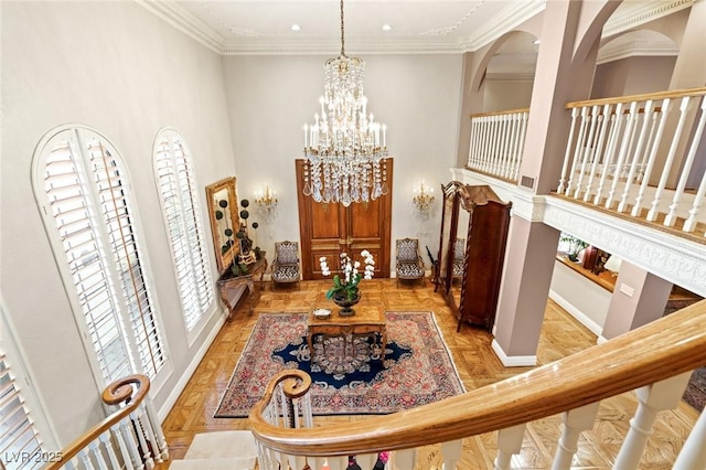 interior space with light parquet flooring, ornamental molding, and an inviting chandelier