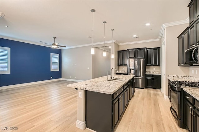 kitchen with pendant lighting, sink, crown molding, stainless steel appliances, and a center island with sink