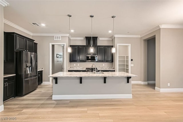 kitchen with a kitchen island with sink, sink, stainless steel appliances, and a kitchen breakfast bar