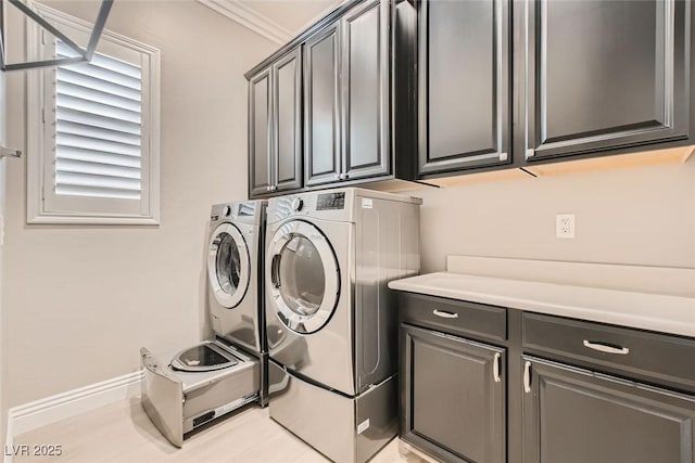 washroom featuring cabinets, washing machine and dryer, and ornamental molding