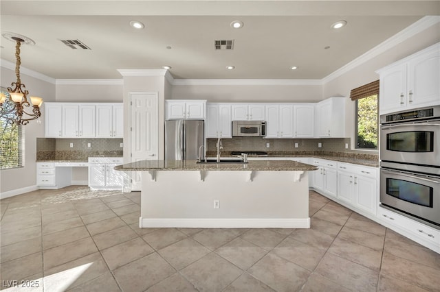 kitchen with stone countertops, appliances with stainless steel finishes, a kitchen island with sink, and light tile patterned floors