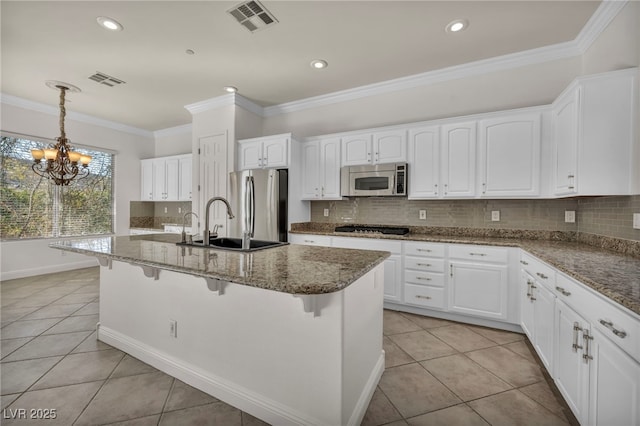 kitchen with appliances with stainless steel finishes, a kitchen island with sink, and white cabinets