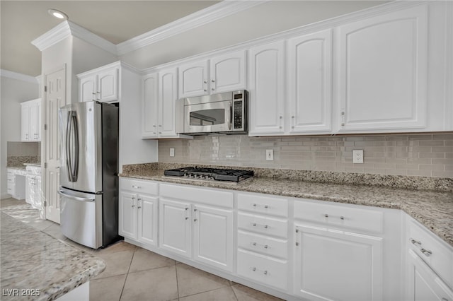 kitchen featuring light tile patterned flooring, appliances with stainless steel finishes, white cabinets, ornamental molding, and light stone countertops