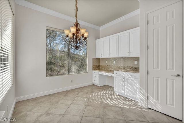 kitchen with light tile patterned floors, hanging light fixtures, tasteful backsplash, built in desk, and white cabinets