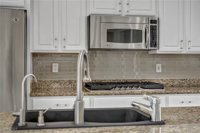 kitchen with dark stone countertops, stainless steel appliances, and white cabinets