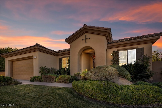 mediterranean / spanish-style house with a garage and a lawn