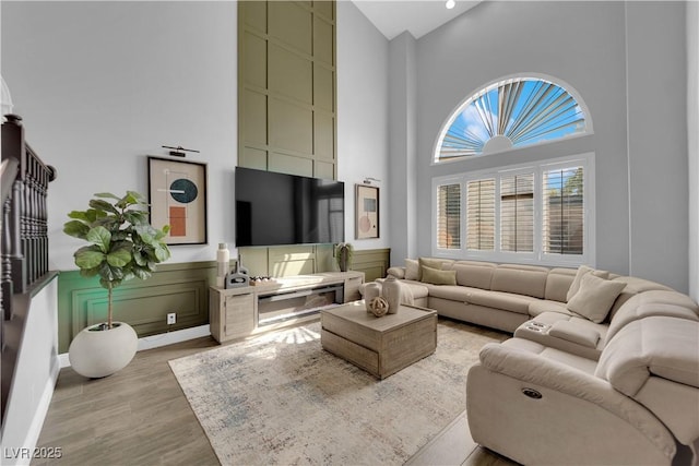 living room with a towering ceiling and light hardwood / wood-style floors