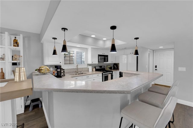 kitchen with appliances with stainless steel finishes, sink, a breakfast bar area, white cabinets, and kitchen peninsula