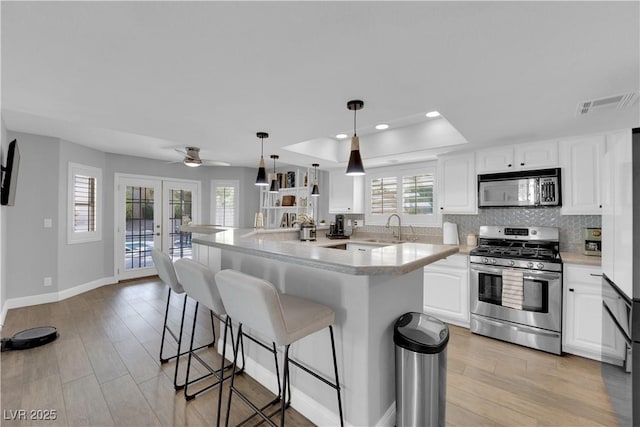 kitchen with white cabinetry, appliances with stainless steel finishes, hanging light fixtures, and french doors