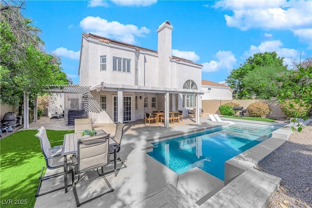 back of house with a fenced in pool, a patio, and a pergola