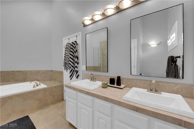 bathroom with a relaxing tiled tub, vanity, and tile patterned flooring