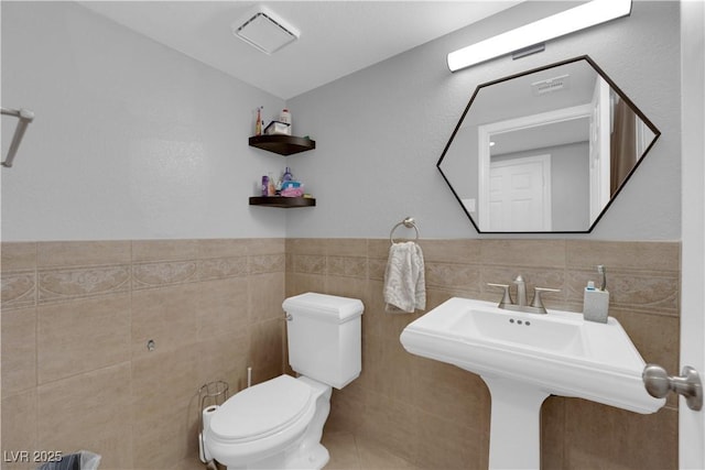 bathroom with tile walls, sink, and toilet