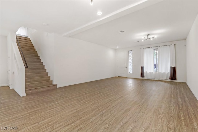 unfurnished living room with beamed ceiling and light hardwood / wood-style flooring