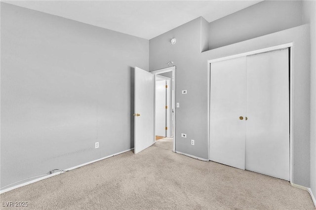 unfurnished bedroom featuring light colored carpet and a closet