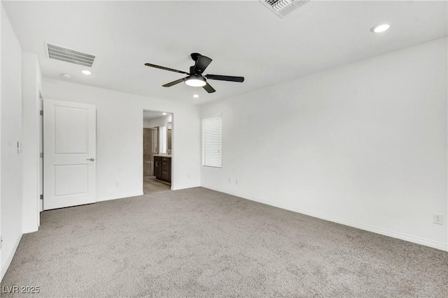 unfurnished bedroom featuring connected bathroom, light colored carpet, and ceiling fan