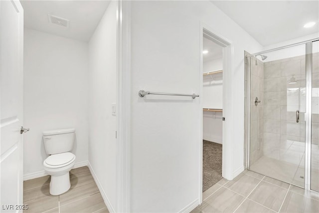 bathroom featuring a shower with door, tile patterned flooring, and toilet