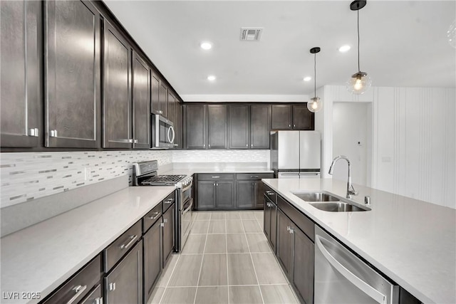 kitchen featuring dark brown cabinetry, sink, appliances with stainless steel finishes, pendant lighting, and backsplash