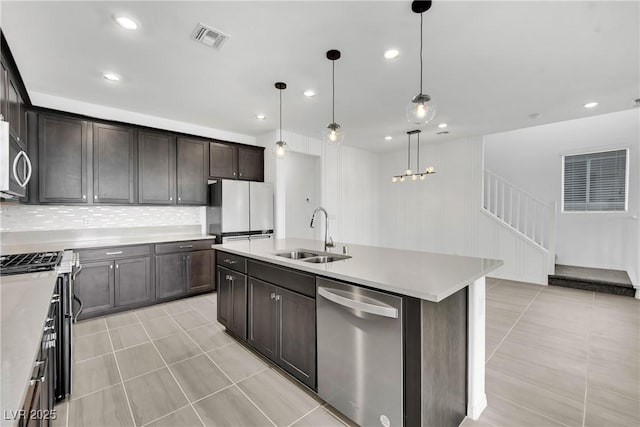 kitchen featuring sink, tasteful backsplash, appliances with stainless steel finishes, an island with sink, and pendant lighting