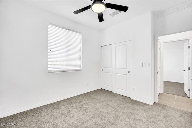 unfurnished bedroom with ceiling fan, light colored carpet, and a closet