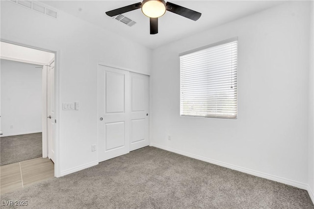 unfurnished bedroom with ceiling fan, light colored carpet, and a closet