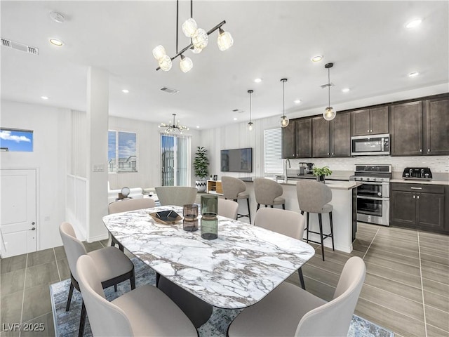 dining space featuring plenty of natural light, sink, and an inviting chandelier