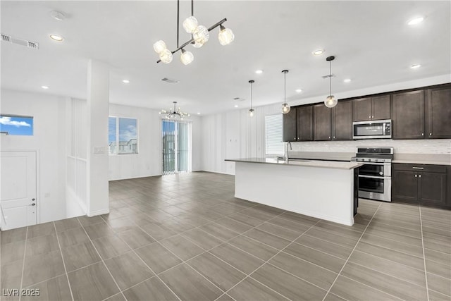 kitchen featuring sink, hanging light fixtures, a center island with sink, a notable chandelier, and stainless steel appliances