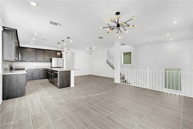 kitchen with pendant lighting, a chandelier, white refrigerator, a kitchen island with sink, and light tile patterned floors