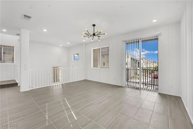 tiled spare room featuring a notable chandelier