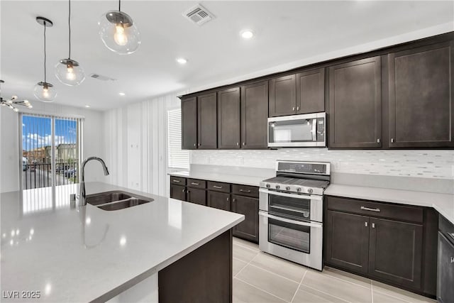 kitchen with sink, decorative light fixtures, dark brown cabinets, light tile patterned floors, and appliances with stainless steel finishes