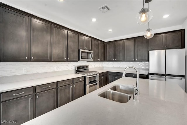 kitchen with hanging light fixtures, appliances with stainless steel finishes, sink, and dark brown cabinetry