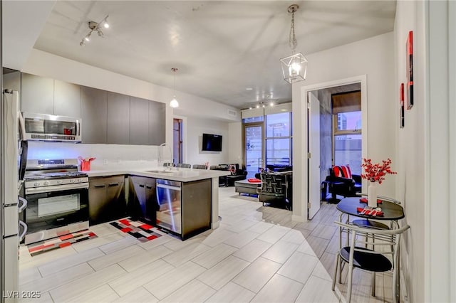 kitchen with hanging light fixtures, appliances with stainless steel finishes, sink, and kitchen peninsula