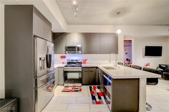 kitchen with sink, gray cabinets, kitchen peninsula, pendant lighting, and stainless steel appliances